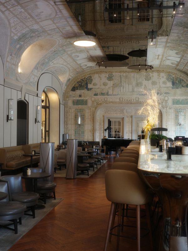 Elegant lounge with ornate ceiling, marble bar, and plush seating.