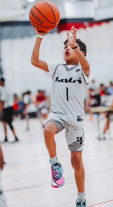 Young basketball player in mid-air preparing to shoot the ball during a game.