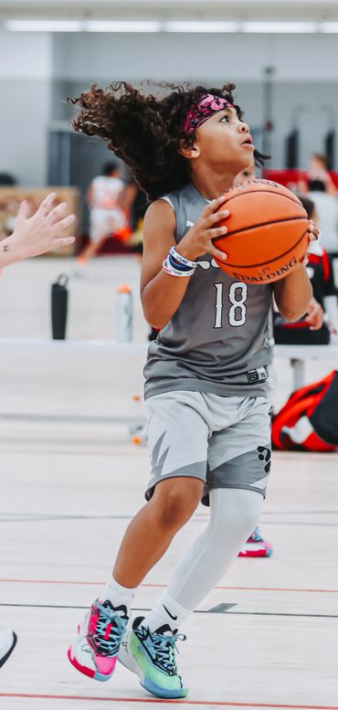 Young basketball player in mid-action holding the ball on an indoor court.