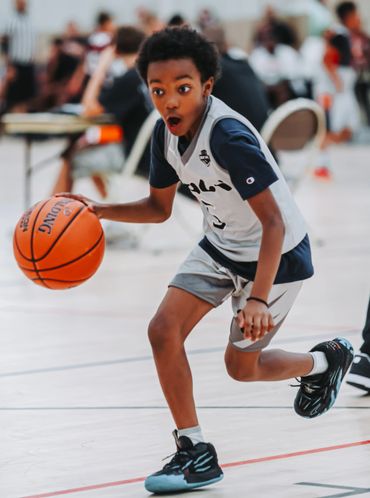 Young basketball player dribbling with focus and surprise.