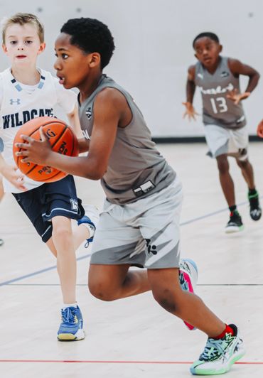 Young boys actively playing basketball in a gymnasium game.