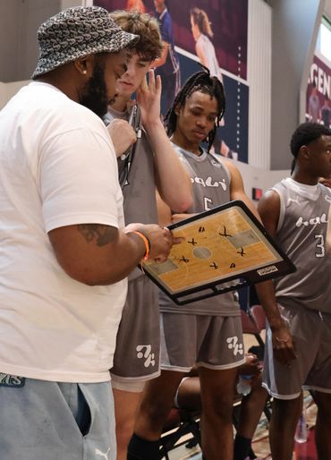 Coach discussing basketball strategy with players using a clipboard.