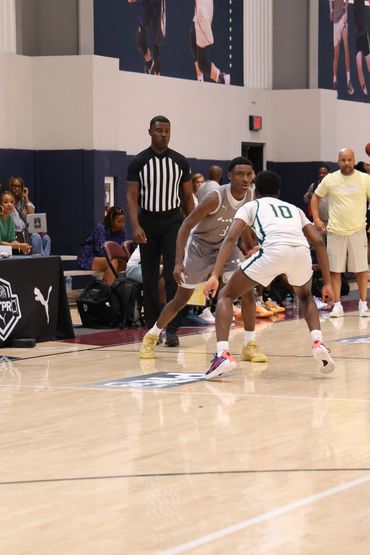 Two basketball players face off with a referee watching closely during a game.