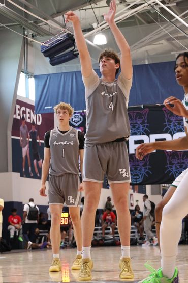Two basketball players in gray uniforms on the court during a game.