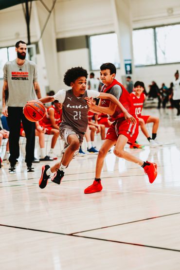 Two young boys fiercely competing in a basketball game indoors.