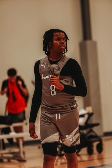 Young basketball player in gray uniform on the court.