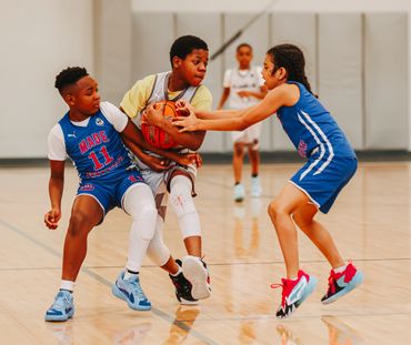 Kids playing intense basketball game indoors, competing for the ball.