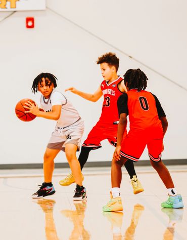 Young boys intensely playing basketball in a gym.