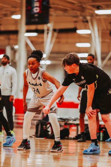 Two young basketball players in defensive stance during a game.