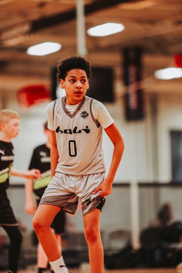 Young basketball player in gray uniform focused on the game indoors.