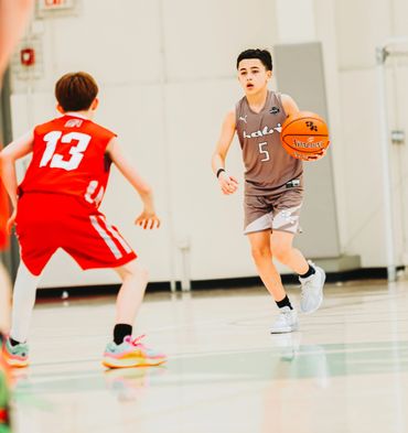 Two boys playing basketball during a game on an indoor court.