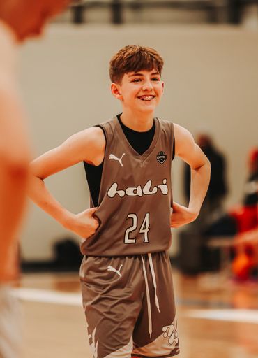 Smiling teenage basketball player in gray uniform number 24 on court.
