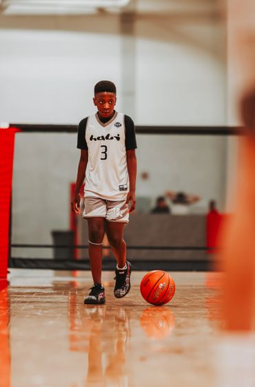 Young basketball player dribbling on an indoor court.