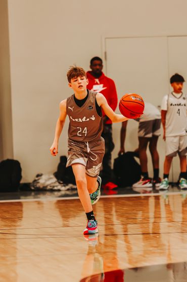 Young basketball player dribbling on indoor court during game.