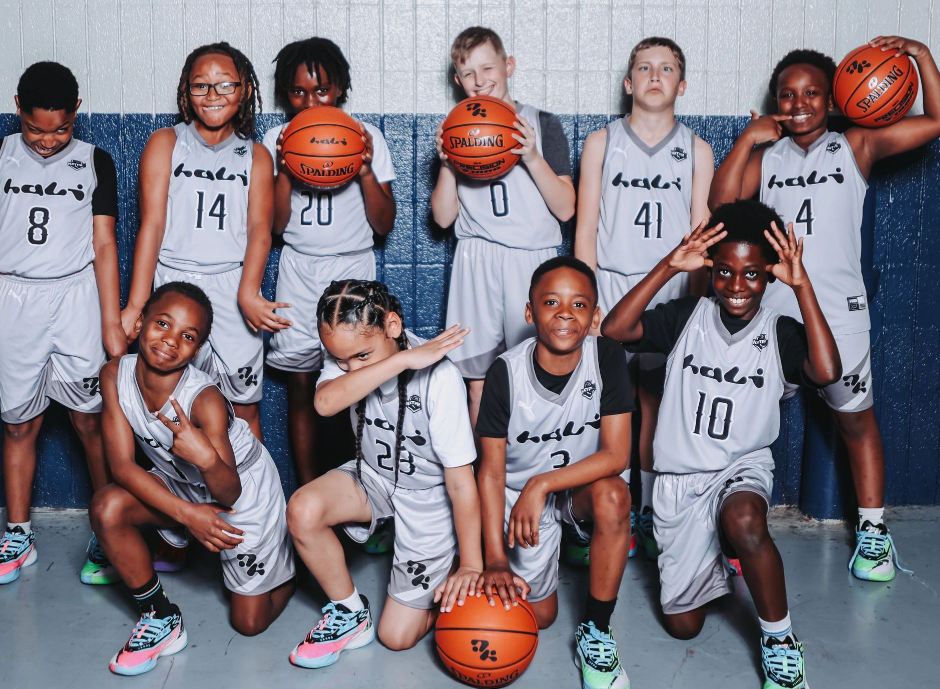 Youth basketball team posing with basketballs and playful expressions.