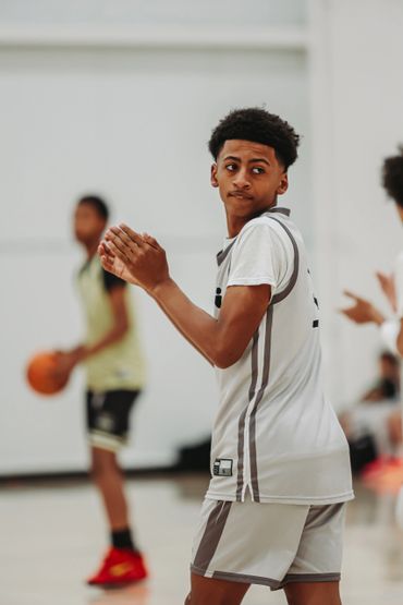 A young basketball player clapping and looking to the side during a game.
