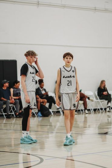 Two young basketball players stand on the court during a game.