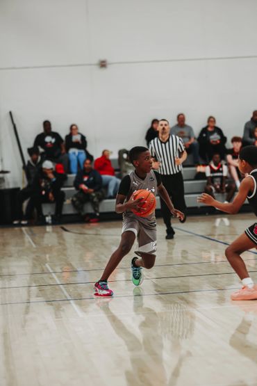 Young basketball player dribbling on indoor court during a game.