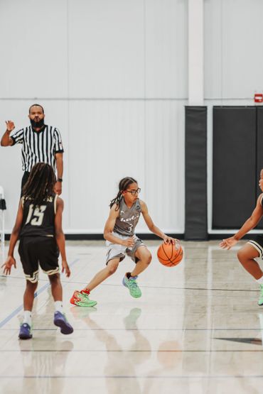 Young basketball player dribbling past defenders on indoor court.
