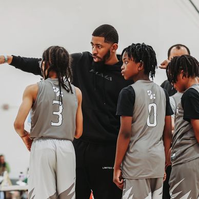 Youth basketball coach instructing players during a game break.