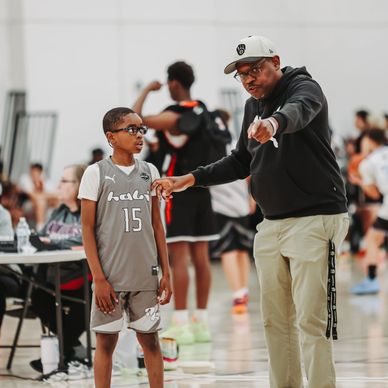 Basketball coach giving instructions to a young player on the court.