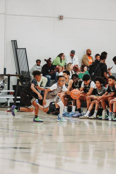 Young basketball players in action during a game with teammates and spectators watching.