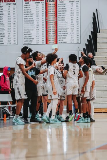 Youth basketball team huddles with coach during game timeout.