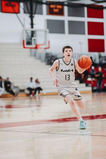 Young basketball player dribbling on court during game.