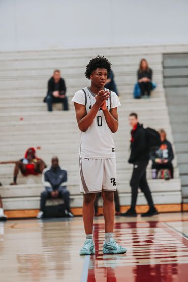 Basketball player in white jersey clapping on the court during a game.