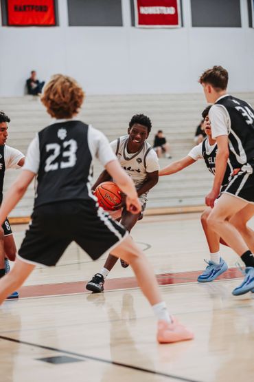Young basketball player dribbling through defenders in a gym.