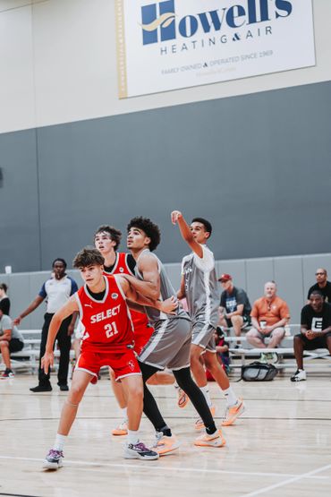Youth basketball game with players in red and gray jerseys actively competing.