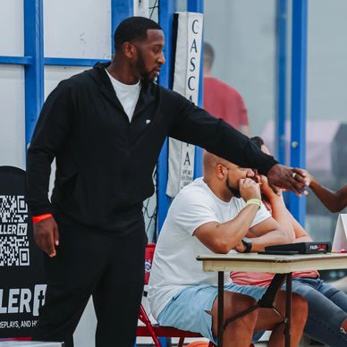 Coach fist bumps young basketball players during a game at the court.