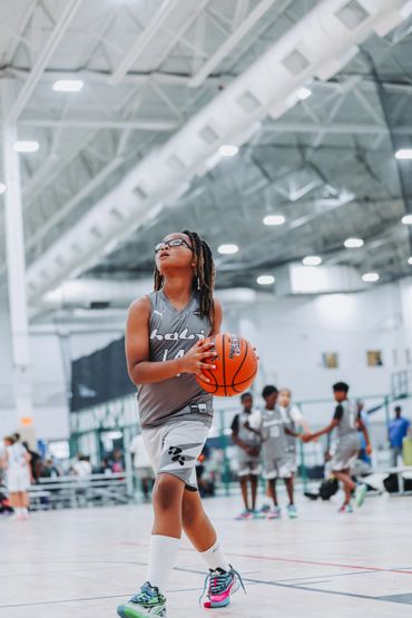 Young basketball player focused, holding the ball on an indoor court.
