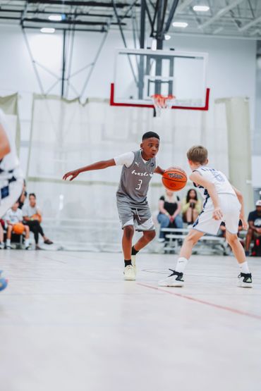 Two young boys playing basketball indoors during a game.