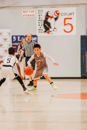 Young boy dribbling basketball during a game on court 5.