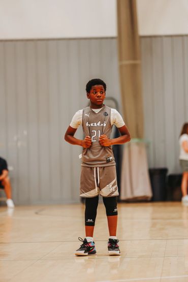 Young basketball player in uniform stands on court during a game.