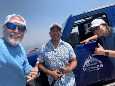 Three happy guests giving a thumbs up beside a Leavenworth Alpine Tours Jeep after a private mountain tour.