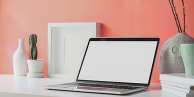 Laptop on white desk in front of peach coloured wall