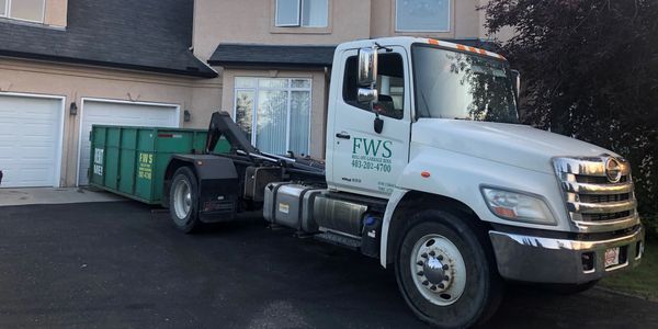 FWS Hino dropping off a bin on a driveway.