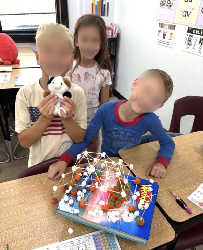 Three kids in a classroom with a science project.
