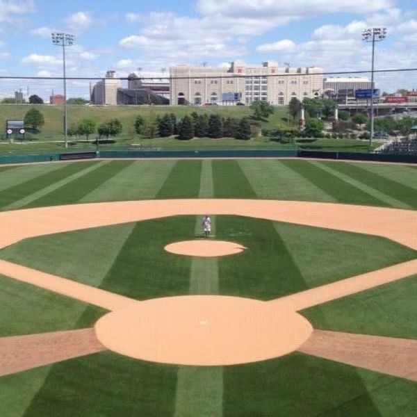A baseball field with a lone player standing on the pitcher's mound.