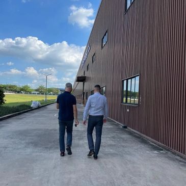 Two men walking beside a large modern building under a blue sky.