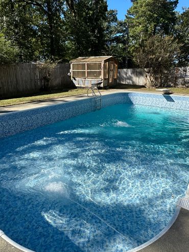 Backyard pool with clear blue water and a small wooden shed.