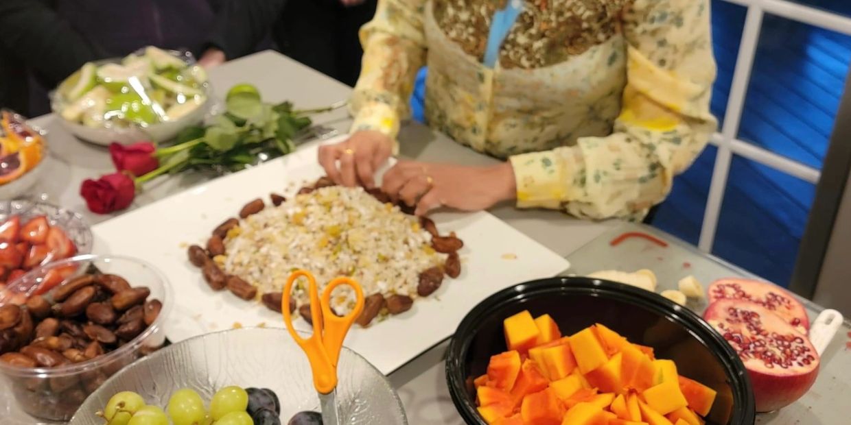 Person prepares food surrounded by fruits and roses on a table.