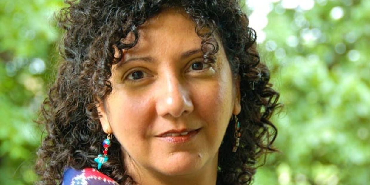 Woman with curly hair and colorful earrings.