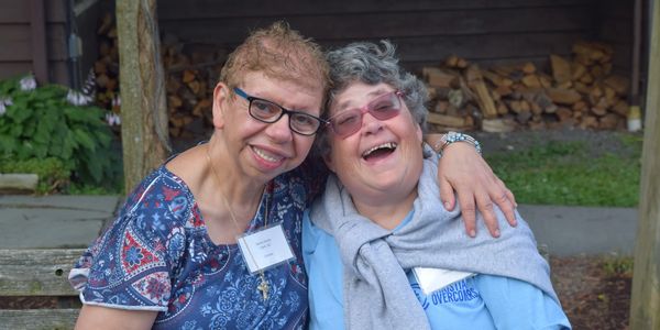 Two elderly women smiling happily together outside.