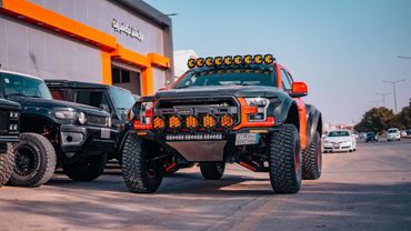 A rugged off-road truck with multiple KC lights and large tires parked on a street.