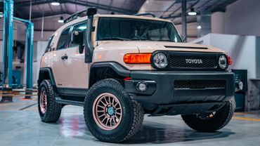A white Toyota off-road SUV with large tires in a garage.