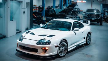 White sports car with racing modifications in a garage.