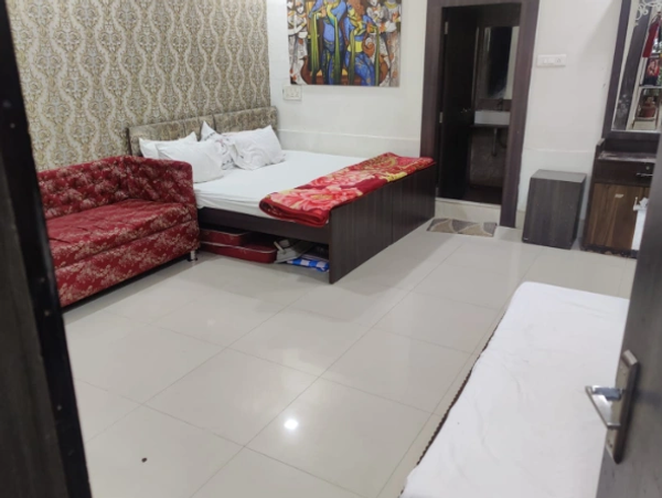 Cozy bedroom with double bed and red patterned sofa.